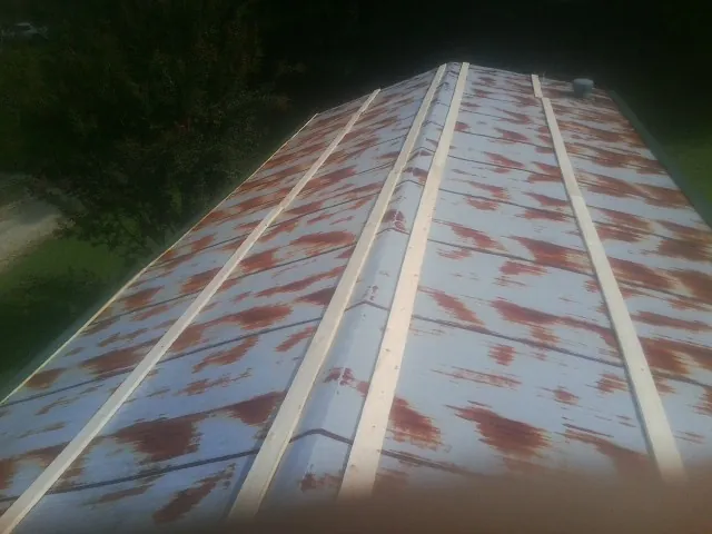 Rusted metal roof panels with new wood purlins before replacement — Storm Damage Roof Repair in Warrensville by Roofing Brothers
