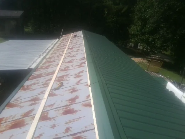 Old rusted panels beside newly installed green metal roofing — Wind Damage Roof Repair by Roofing Brothers in Warrensville