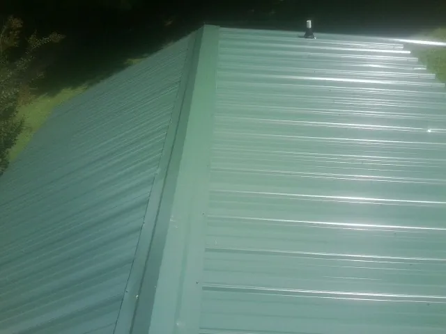 New green metal panels meeting at the ridge of a roof — Flat Roof Repair work by our crew in Warrensville