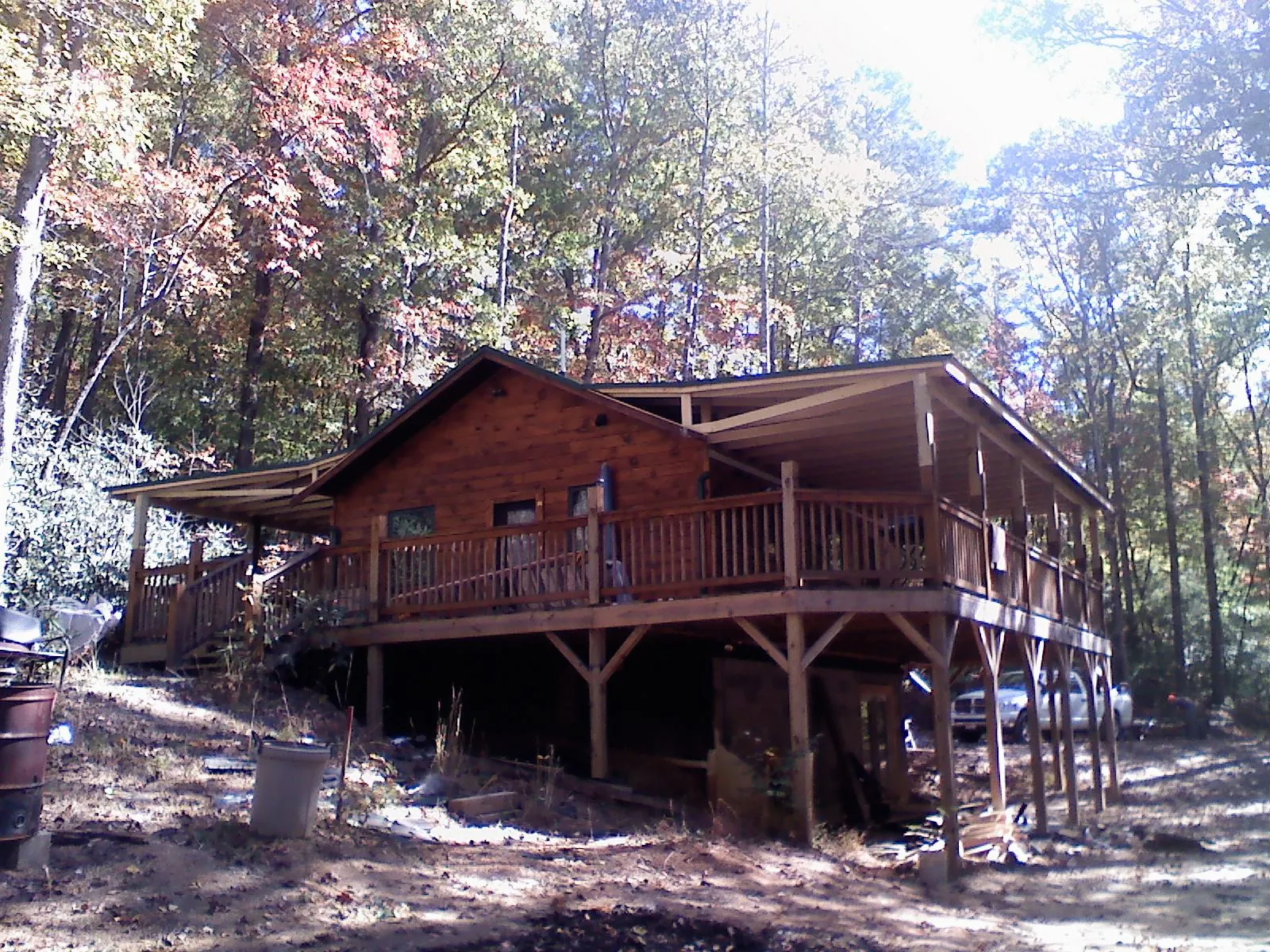 Log cabin with a wraparound porch and metal roof in the fall in Warrensville