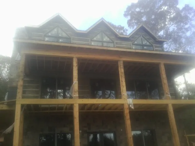 Dormers and porch framing on a large log home under construction — Roof Coating work by our crew in Warrensville