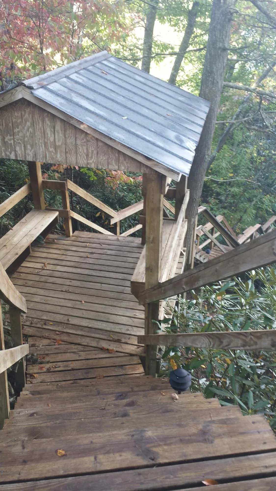 Metal roofed shelter over wooden steps on a wooded walkway — Skylight Repair & Installation work by our crew in Warrensville