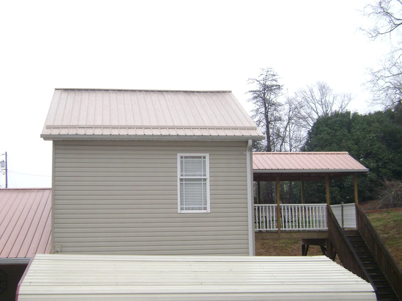 Tan metal roofs on a two story addition and attached porch, from a Roof Replacement job in Warrensville