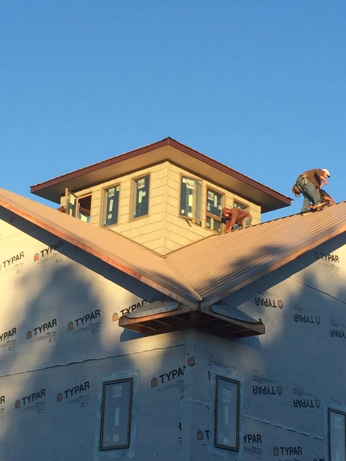 Roofers working around a rooftop cupola on a new metal roof at sunset — Roof Waterproofing in Warrensville by Roofing Brothers